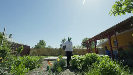 Rumänin-Trägt-Altes-Tongefäß-Im-Garten---Weitwinkelaufnahme