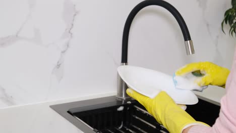 cropped image of an attractive young woman washing dishes while cleaning the house