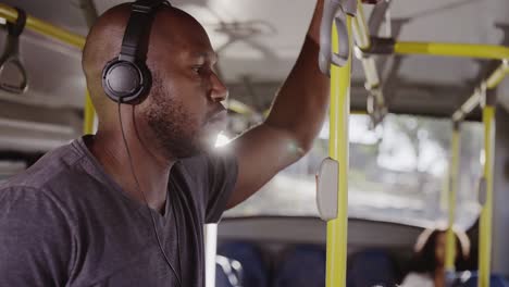 man with headphones standing on a public bus