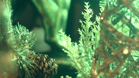 primer plano de un árbol de plástico con piñas para adornos navideños, iluminado por luces