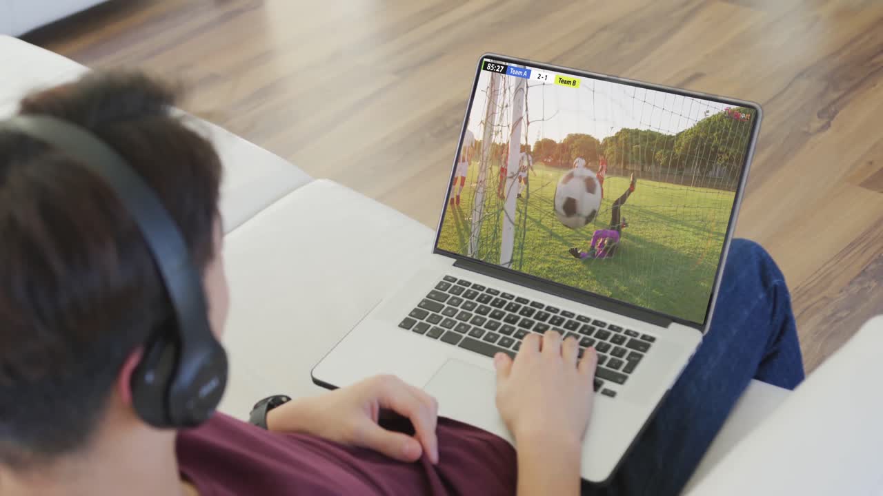 video de un hombre caucásico sentado en el sofá y viendo fútbol en la computadora portátil en casa