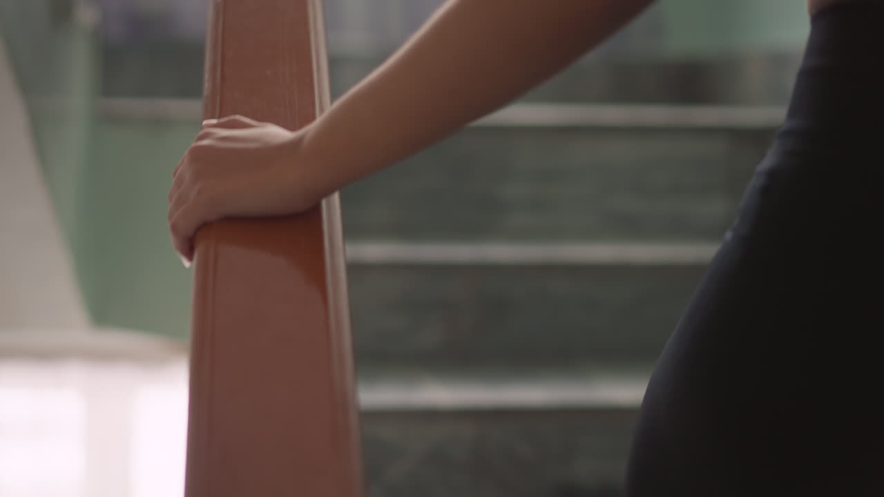 Side view of person climbing staircase with hand resting on glossy handrail, marble steps in background, calm upward motion showing balance, safety, steady movement in indoor setting with soft light