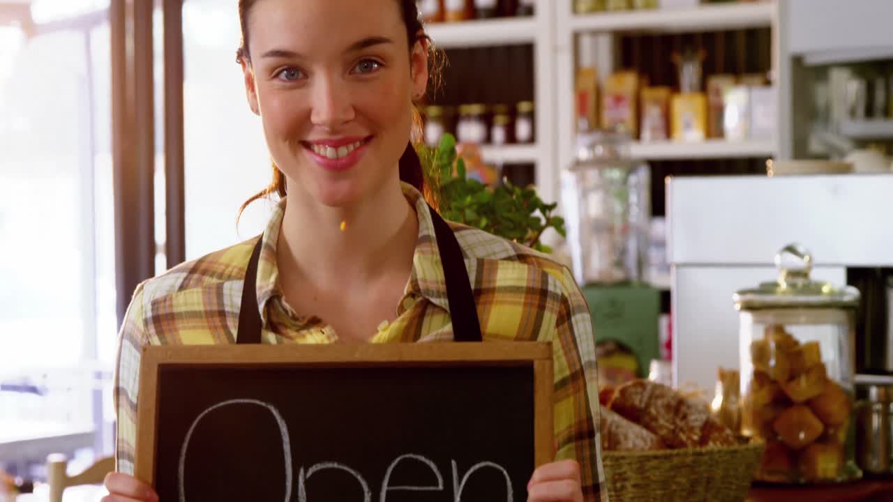 retrato de una camarera mostrando una pizarra con un letrero abierto