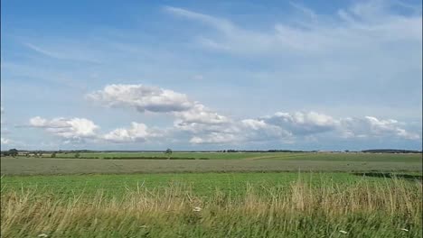 a vehicle travels through the british countryside, the view looking out at the landscape as the vehicle travels by