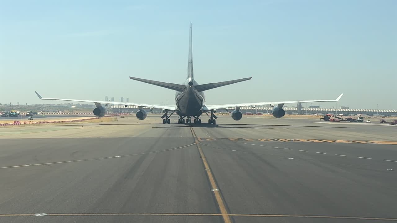 A pilot’s perspective from cockpit of a massive 4-engine jet taxiing slowly and heavely at Madrid airport in a hazy and scorching summer morning