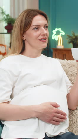 Pregnant woman enjoys decaf coffee cup steam thoughtful gaze into distance calm quiet moment indoors