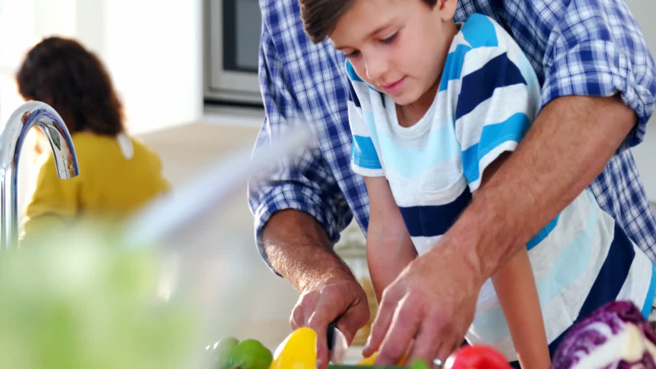 padre e hijo cortando verduras en la cocina