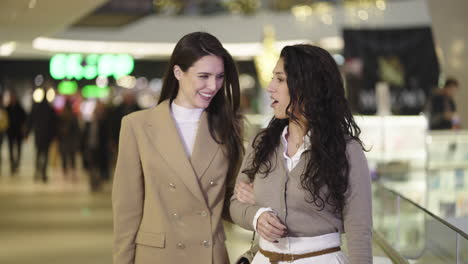 two women talking and walking through a shopping mall