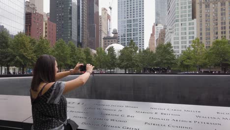 female tourist taking photos at 9 11 memorial museum, new york usa