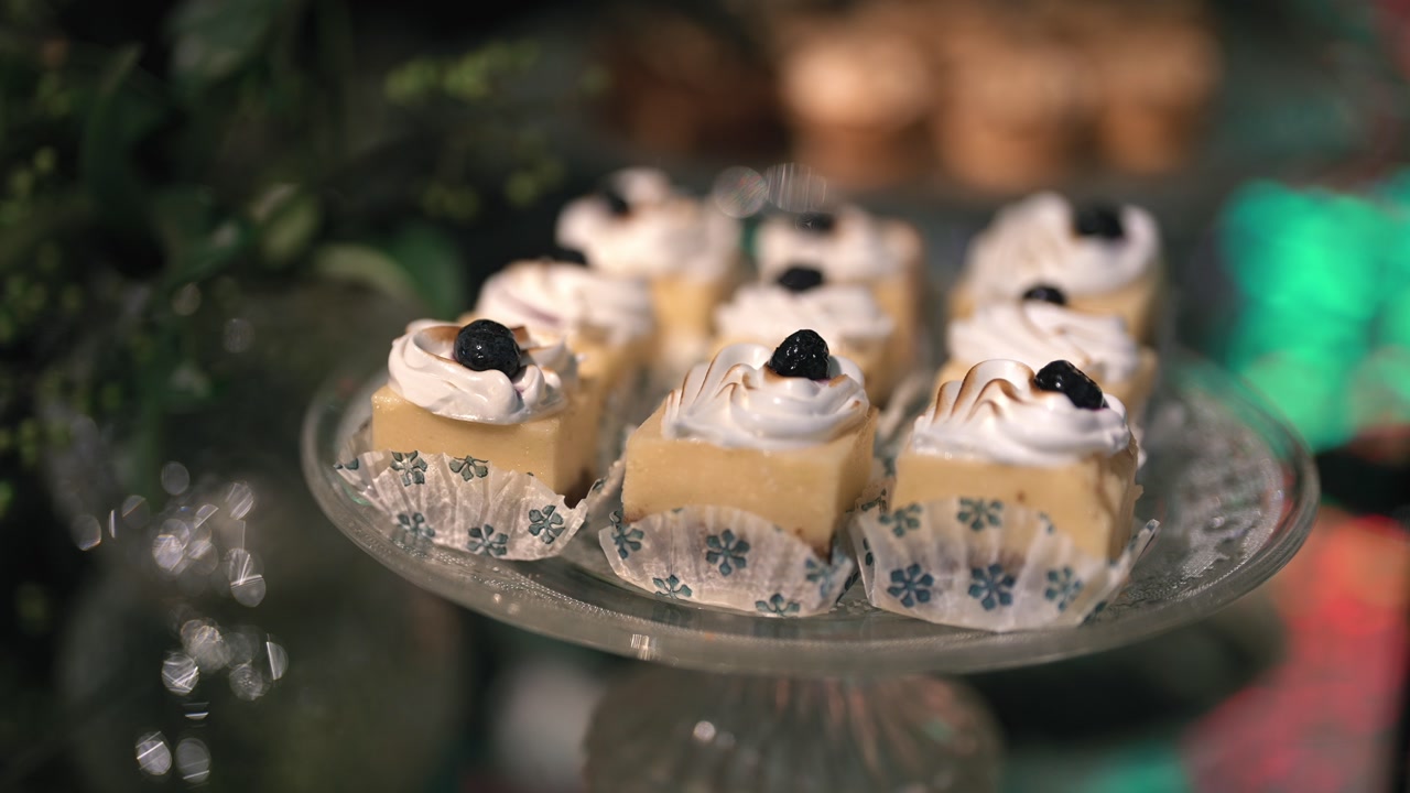 Close-up shot of individual mini pastries topped with whipped cream on a glass tray.