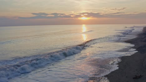 aerial: amazing sunset over waves, sliding view across pacific mexican beach