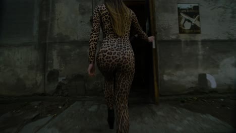 woman in leopard print jumpsuit walking through urban alleyway