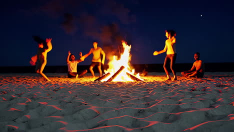 amigos disfrutando de una fogata en la playa por la noche