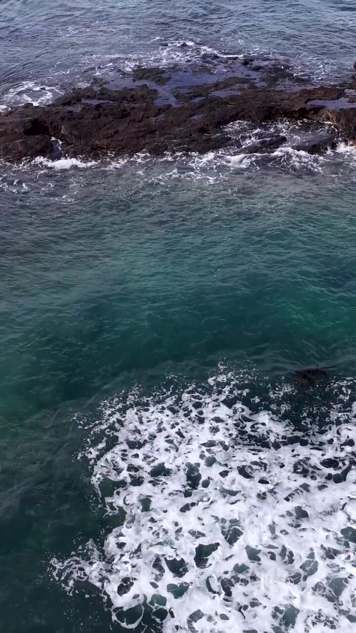 Vista aerea di onde oceaniche turchesi che si infrangono su scure rocce vulcaniche a Flinders, Australia.