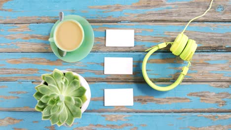 una taza de té, planta de aloe vera, tarjetas de visita y auriculares