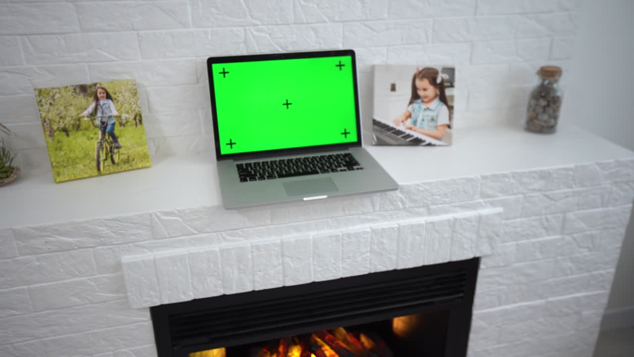 una computadora portátil de pantalla verde sentada en un escritorio de trabajo en casa junto a una lámpara de escritorio.