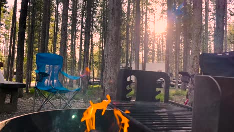 The-morning-sun-shines-through-tall-logepole-pine-trees-at-Bull-Trout-Campground-and-a-morning-fire-in-Idaho