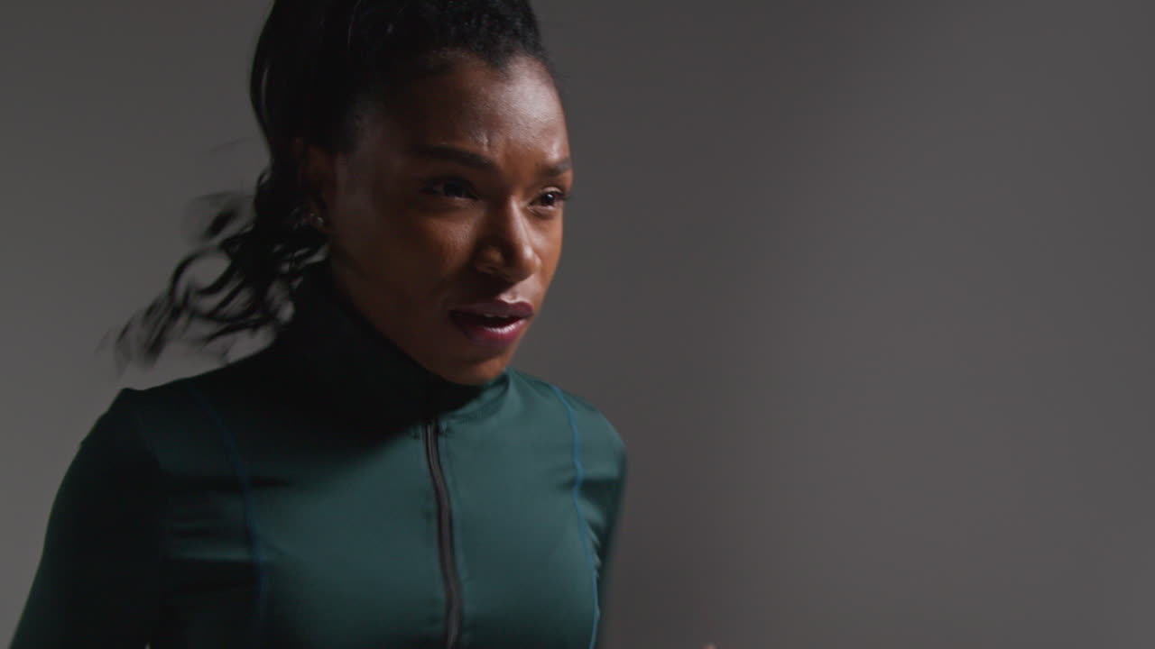 fotografía de cerca de una atleta que lleva un traje de entrenamiento en una clase de gimnasia corriendo en el lugar contra un fondo plano 2