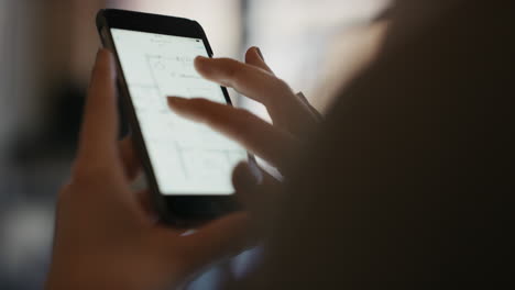 Close-up-of-womans-hands-using-smart-phone-technology-to-read-architectural-plans