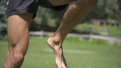 joven caucásico en forma atractiva ejercitándose al aire libre saltando ejercicio con fondo de vegetación verde a cámara lenta