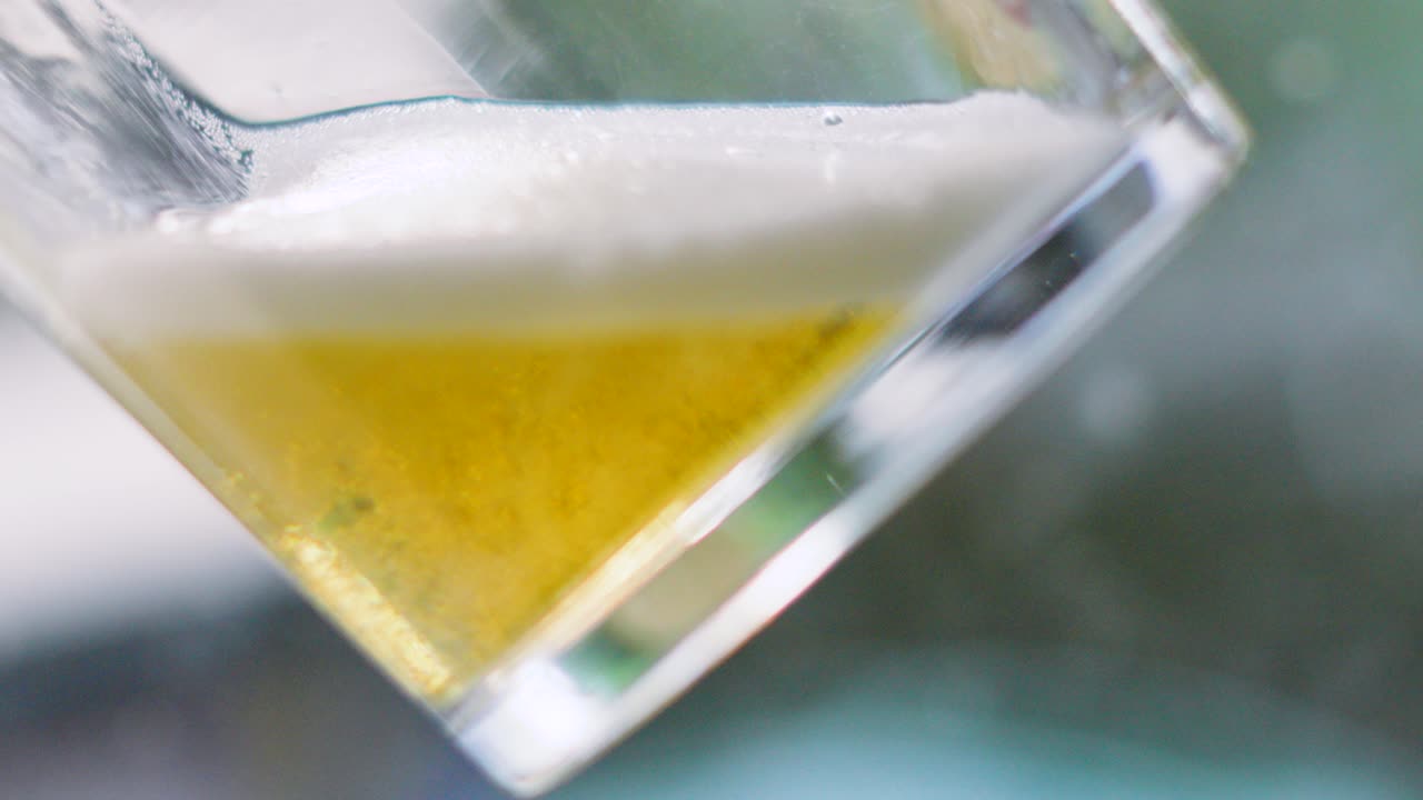 Lager Beer Slowly Pouring into Clear Pint Glass with Vibrant Froth and Color. Alcoholic Drink Enjoyed Outside in Summer