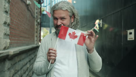 man holding a canadian flag in an urban setting