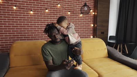 African-american-father-busy-with-smartphone-while-baby-son-near-him-bored-disturb-him