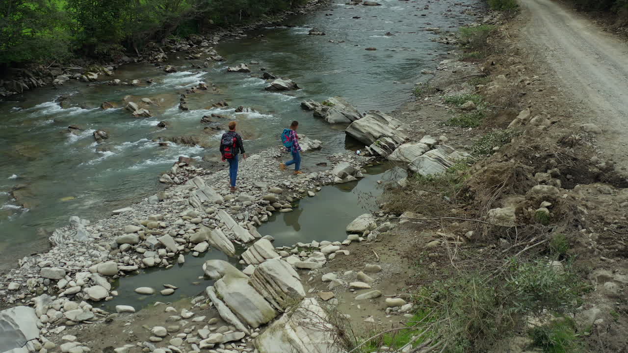 excursionistas cruzando el río vista de avión no tripulado nublado día de primavera buscando vacaciones de aventura