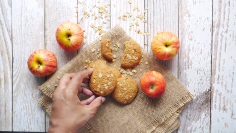 hand reaching for an apple oatmeal cookie on a rustic wooden table