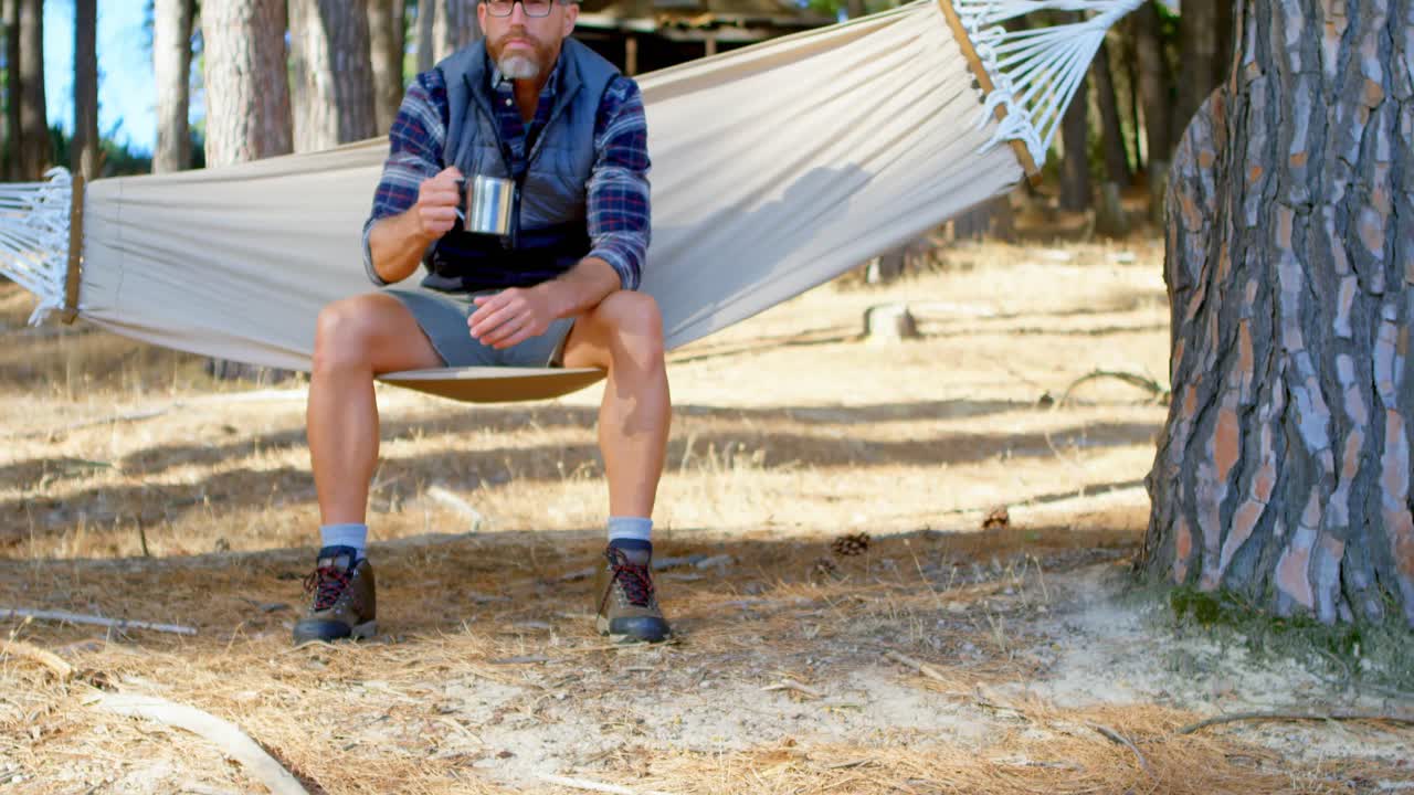 hombre tomando café mientras se relaja en una hamaca 4k