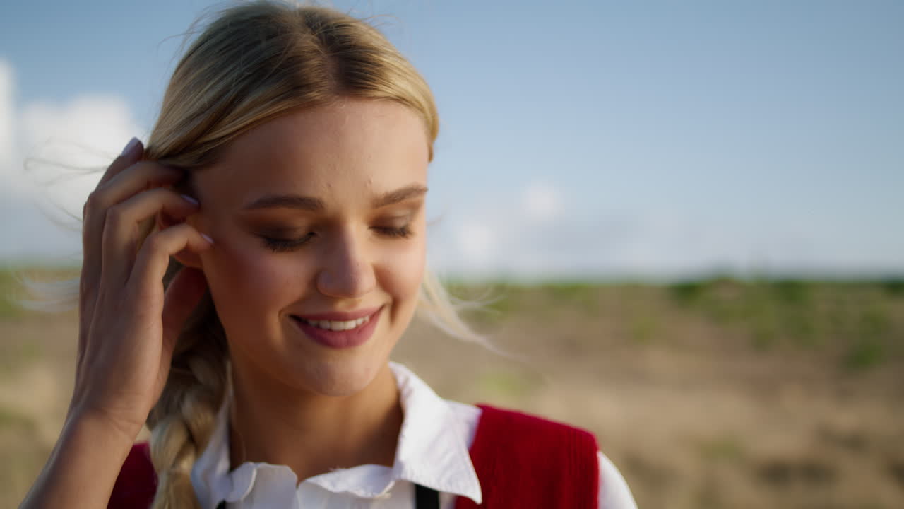 미소 짓는 모델이 야외에서 머리카락을 곧게 한다. 행복한 여성 얼굴 클로즈업