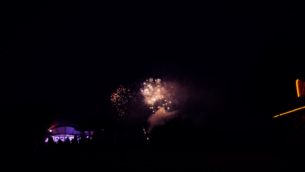 fuegos artificiales por la noche en un área natural abierta con una tienda iluminada y una casa