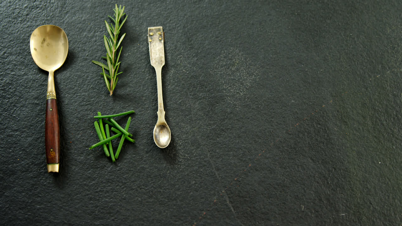 Two metal spoons with chives and rosemary 4k