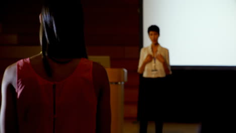 joven empresaria haciendo preguntas a una oradora asiática durante un seminario en el auditorio 4k