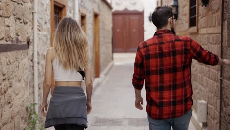 traveler couple walking narrow streets in historical old town, rear view