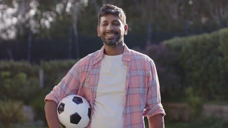 holding soccer ball, man smiling outdoors in casual clothes