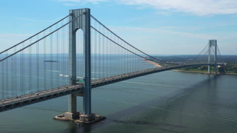 Luftaufnahme-Der-Verrazano-Brücke,-Während-Die-Drohnenkamera-An-Einem-Sonnigen-Morgen-Nach-Rechts-Schwenkt-Und-Staten-Island-Und-Die-Gewässer-Darunter-Betrachtet,-Orbit-1