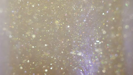 close-up of glitter floating in vodka. colorful gold paint mixing in water. ink swirling underwater. cloud of silky ink. macro view