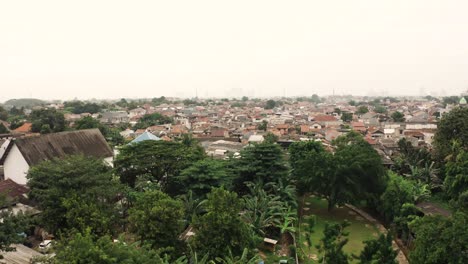 rising drone shot showing poor slum neighborhood of jakarta town during dense foggy sky, indonesia