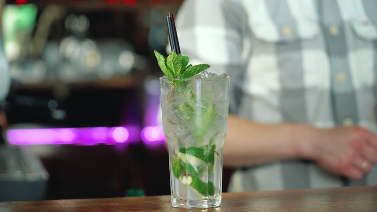 Barman decorates a ready-made cocktail with lime that stands on the bar counter