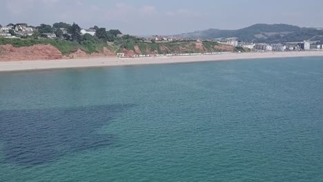 산 꼭대기에 집이 있는 리조트와 마을을 보여주는 영국 시턴의 쥐라기 해안선을 따라 드론이 이동합니다.