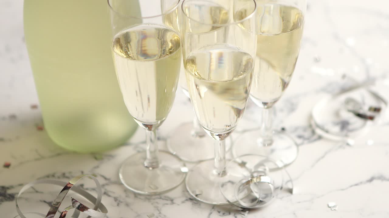 Bicchieri da champagne e bottiglia posti su sfondo di marmo bianco.