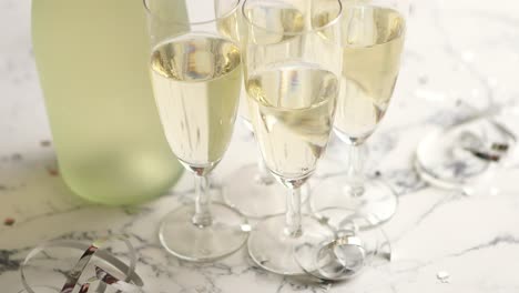 champagne glasses and bottle placed on white marble background