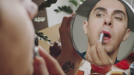 transgender man looking in mirror and putting on lipstick