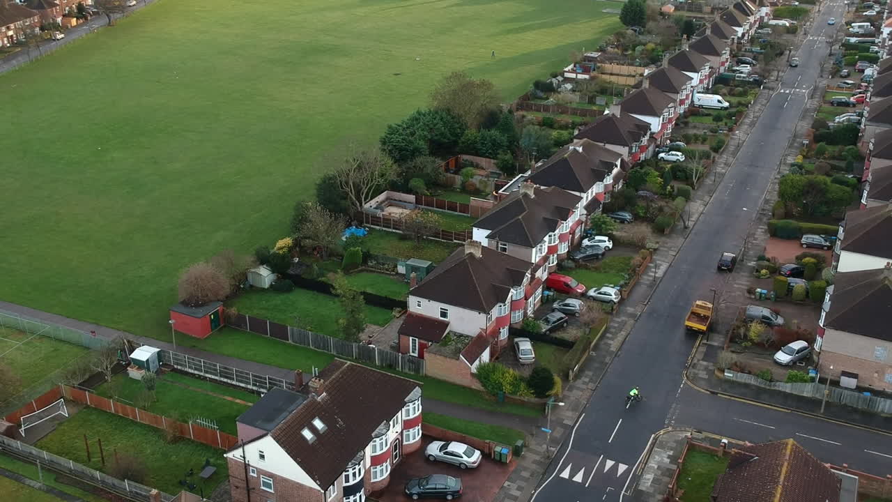 Aerial Shot of Mottingham, South East London: Terrace Houses, Green Space, and Cyclist Riding Along a Long Road