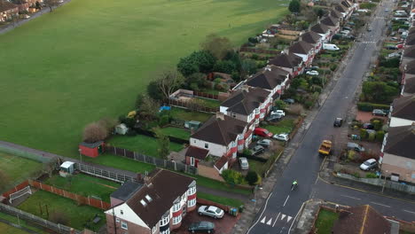 aerial shot of mottingham, south east london: terrace houses, green space, and cyclist riding along a long road
