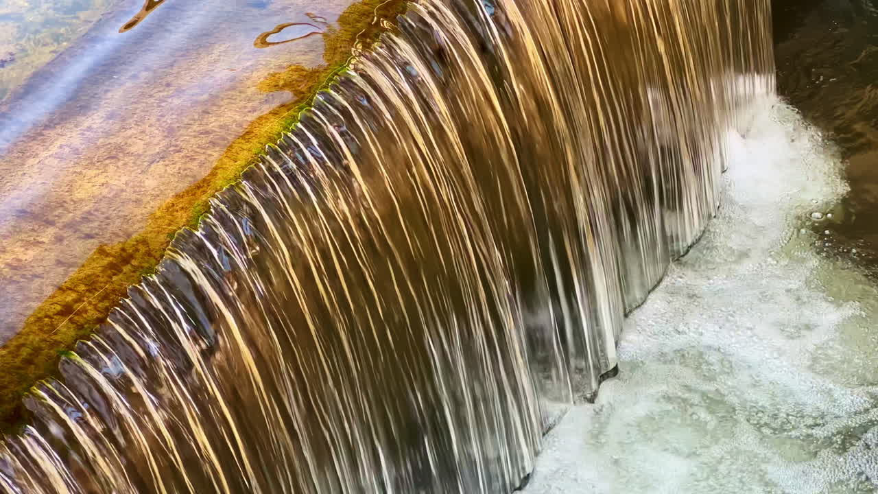 Acqua che scorre a cascata su rocce levigate creando un'atmosfera serena in un tranquillo ambiente naturale a mezzogiorno