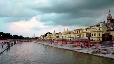 Peregrinos-En-El-Tranquilo-Lago-Del-Río-Sarayu-Bajo-Un-Cielo-Nublado-Junto-Al-Templo-Ram-En-La-Ciudad-De-Ayodhya,-India