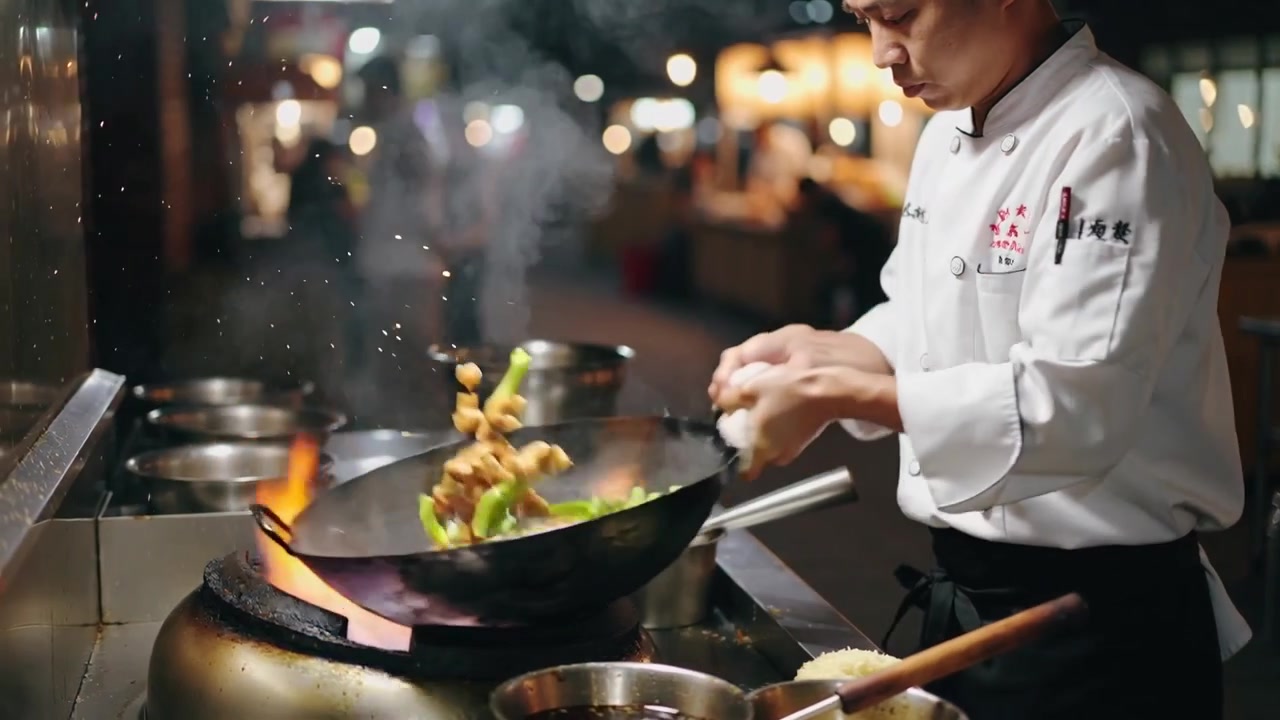 Flipping chef in jacket tossing veg, meat over flaming wok at night market, bowls, copy space