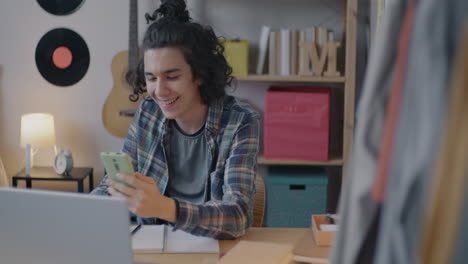 teenager using laptop and phone in bedroom